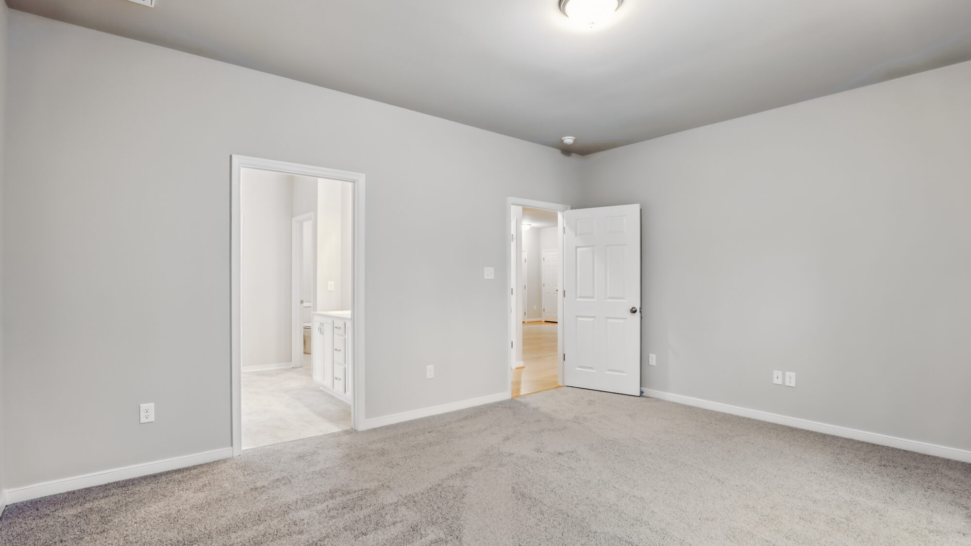 Empty room with gray walls, carpeted floor, and open doors in Bethany’s Somerset Hill community.