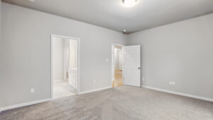 Empty room with gray walls, carpeted floor, and open doors in Bethany’s Somerset Hill community.