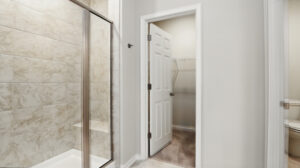 Walk-in shower with glass door in Somerset Hill, next to an open door leading to a carpeted Bethany closet with wire shelves.