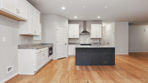Modern Somerset Hill kitchen with white cabinets, granite counters, island, and hardwood floors in open-plan Bethany space.