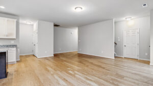 Modern living space in Somerset Hill with light wood floors, white walls, and ceiling lights near the kitchen.
