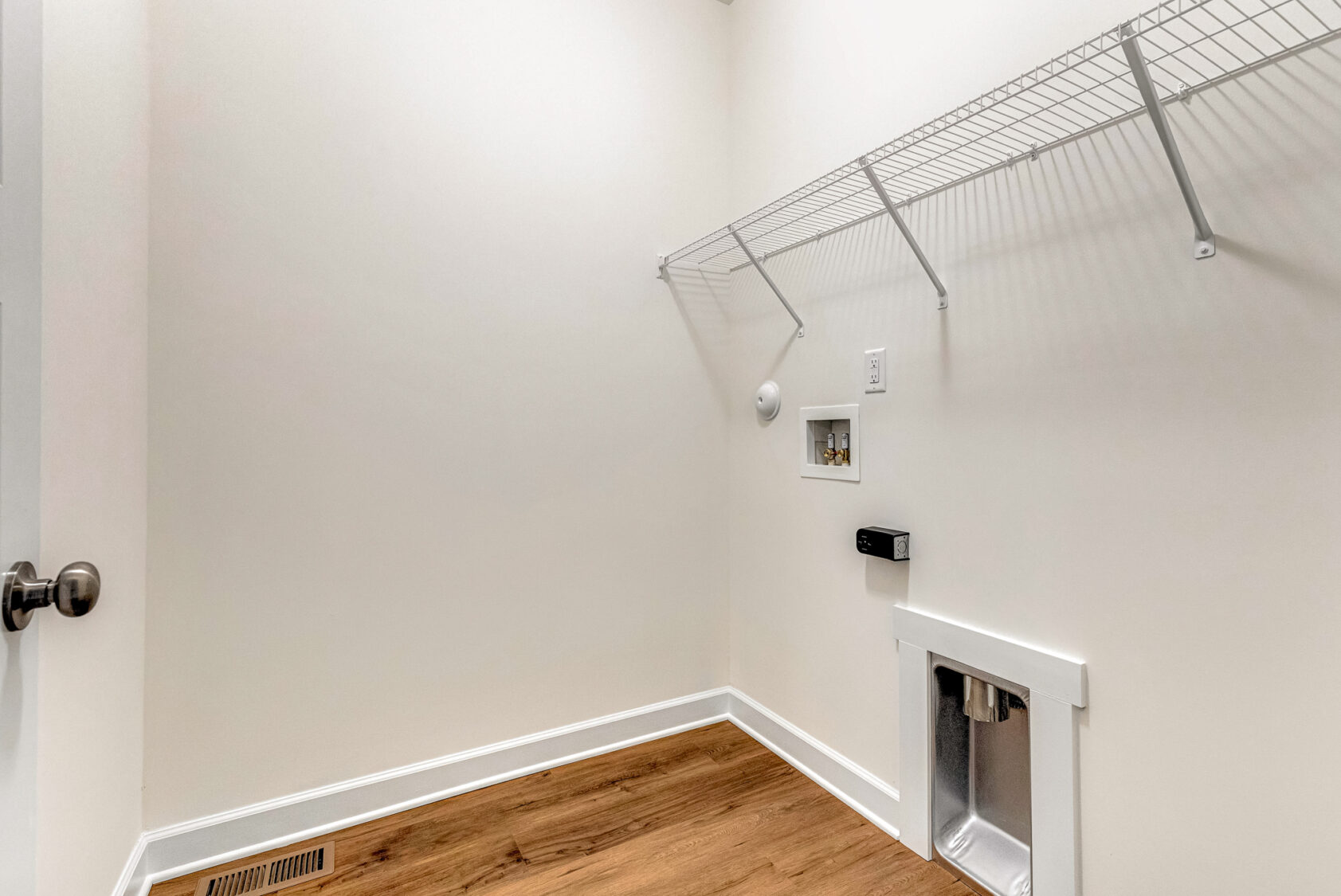 Empty Somerset Hill laundry room with a wire shelf, washer and dryer hookups, and light wood flooring.