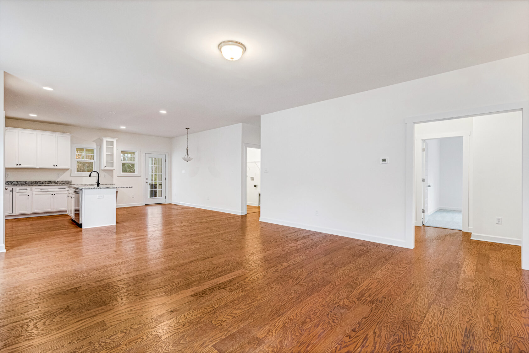 Spacious open-plan room at Kate Somerset Hill with hardwood floors, white walls, and a modern kitchen.