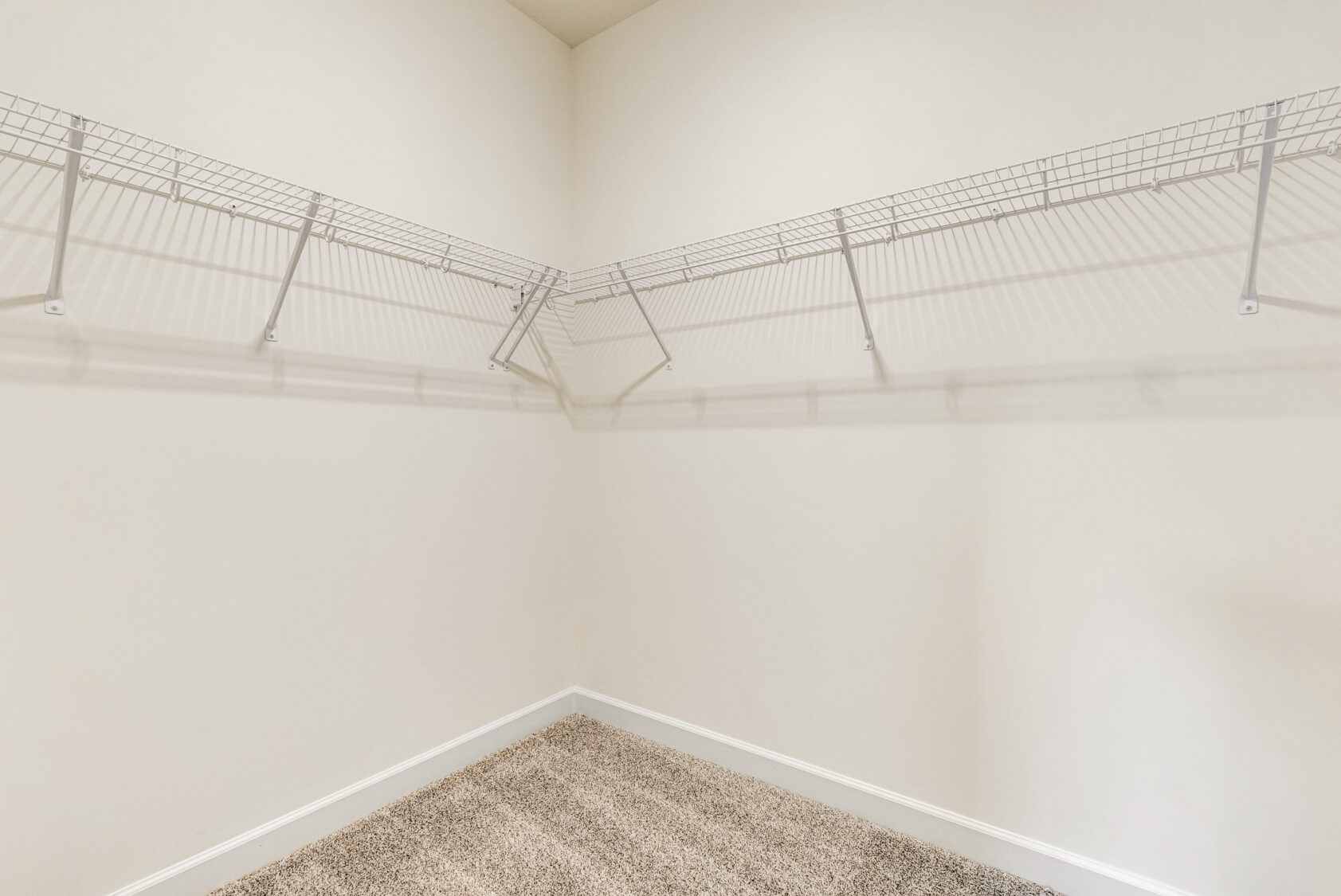 Spacious Somerset Hill walk-in closet with beige carpet and white wire shelves along two walls.