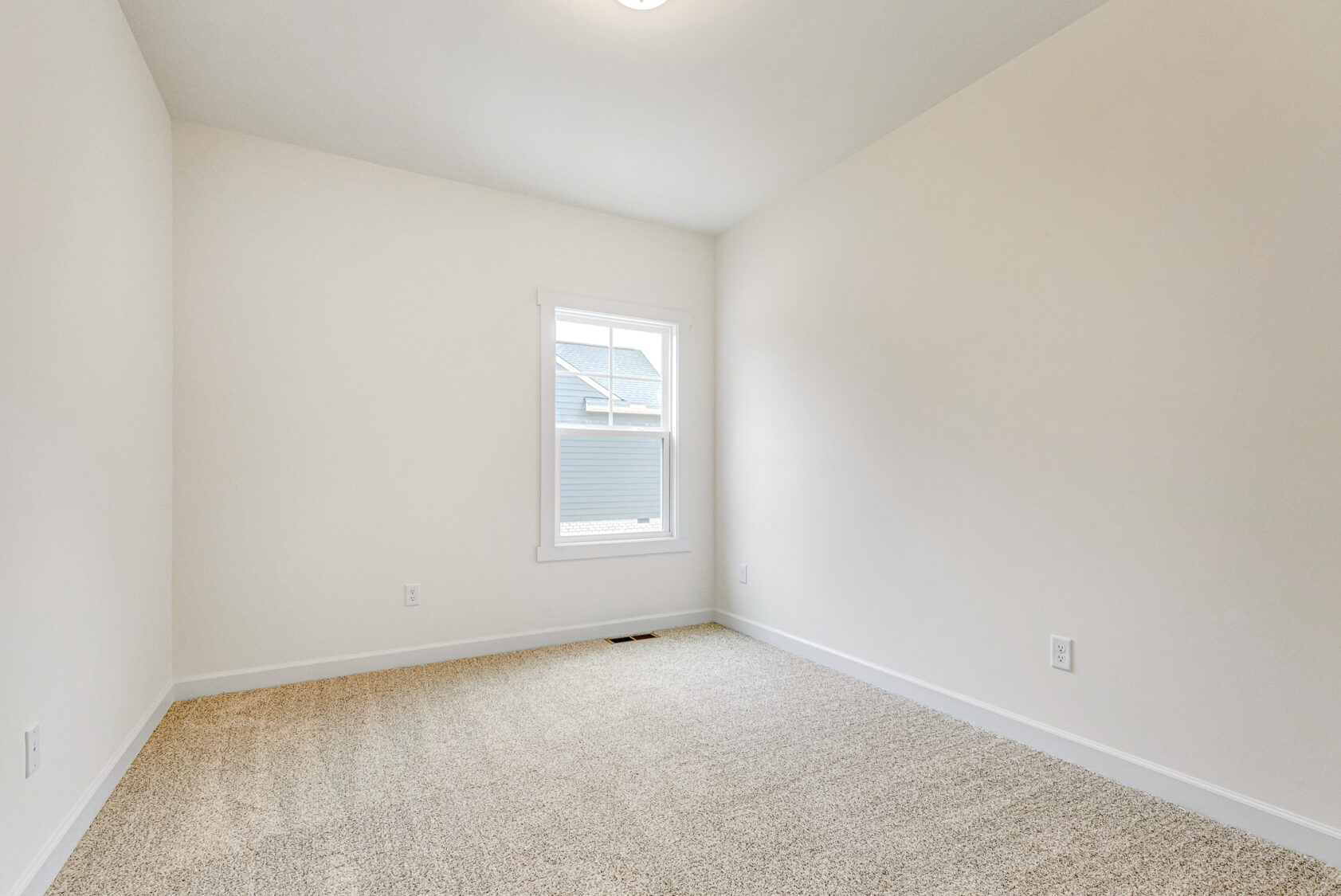 Bright empty room at Somerset Hill with beige carpet, white walls, and a window filling the space with natural light.