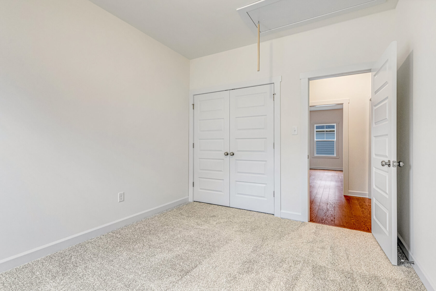 Empty bedroom at Somerset Hill features beige carpet, white walls, double closets, and an open door to the hallway.