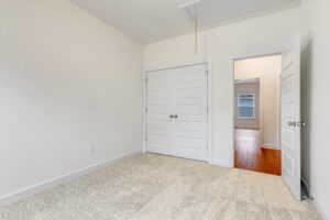 Empty bedroom at Somerset Hill features beige carpet, white walls, double closets, and an open door to the hallway.