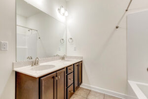 Modern Somerset Hill bathroom with double sink vanity, large mirror, tub, and beige tile floor—styled by Kate.