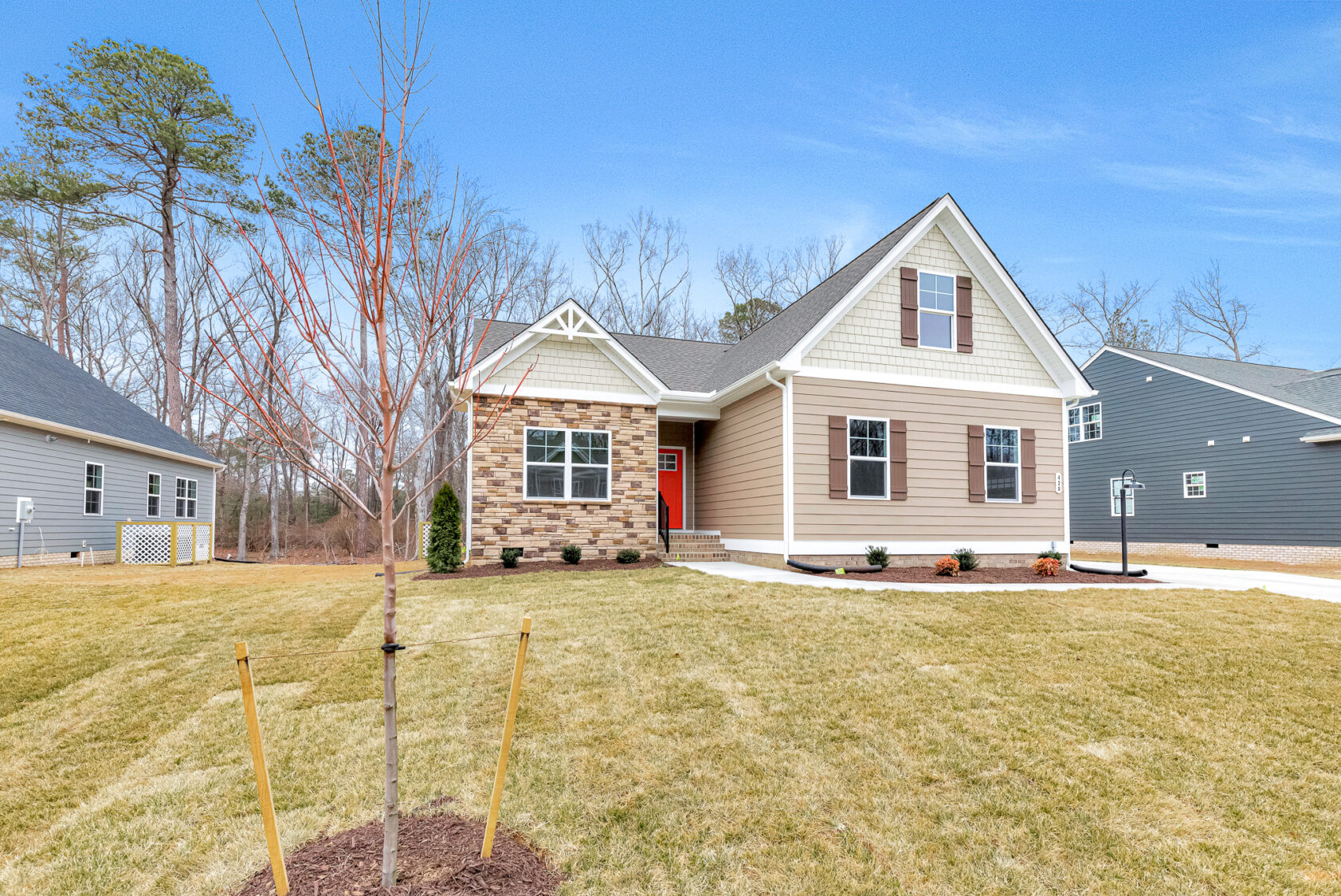 Charming Somerset Hill single-story with stone and siding exterior, gabled roof, and red door on a spacious lawn.
