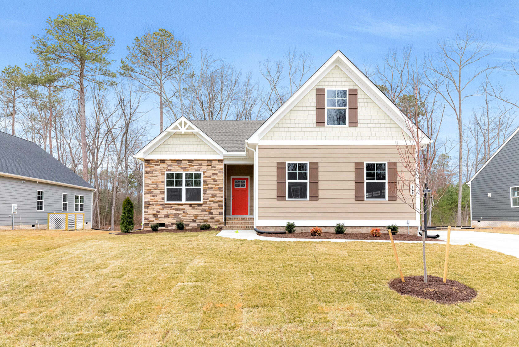 Single-story Somerset Hill house with beige siding, red door, front lawn, and clear blue sky.