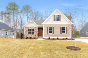 Single-story Somerset Hill house with beige siding, red door, front lawn, and clear blue sky.