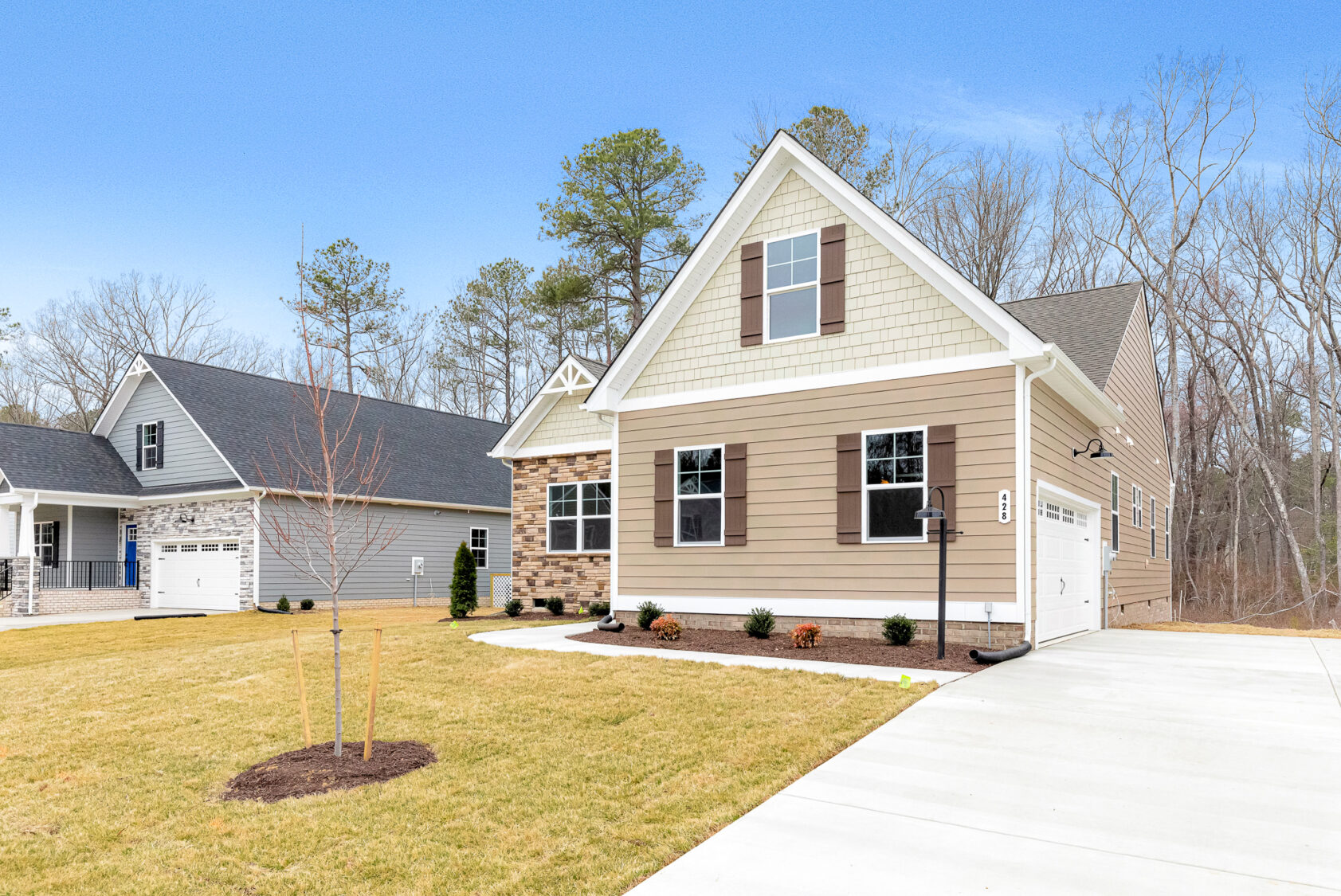 Modern Somerset Hill suburban house with beige siding, brick accents, garage, and a neat lawn under a clear blue sky.