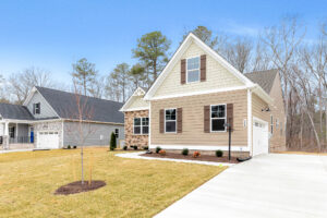 Modern Somerset Hill suburban house with beige siding, brick accents, garage, and a neat lawn under a clear blue sky.