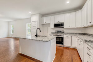 Modern Somerset Hill kitchen with white cabinets, granite counters, island, stainless appliances, and wooden floors.