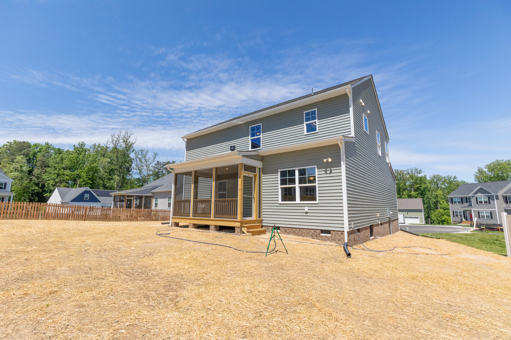 Newly built two-story house on Lot 26, with a screened porch, large yard, and clear blue sky in Poplar Village.