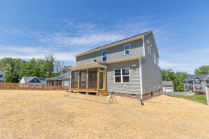 Newly built two-story house on Lot 26, with a screened porch, large yard, and clear blue sky in Poplar Village.