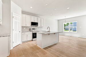 Bright, modern kitchen in Lot 26 at Poplar Village with white cabinets, island, and open dining area.