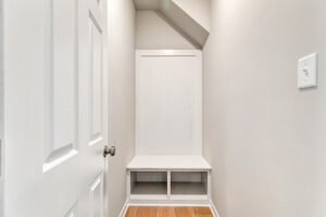 White built-in bench with cubbies beneath and paneled back, set in a Poplar Village Lot 26 nook with light walls.