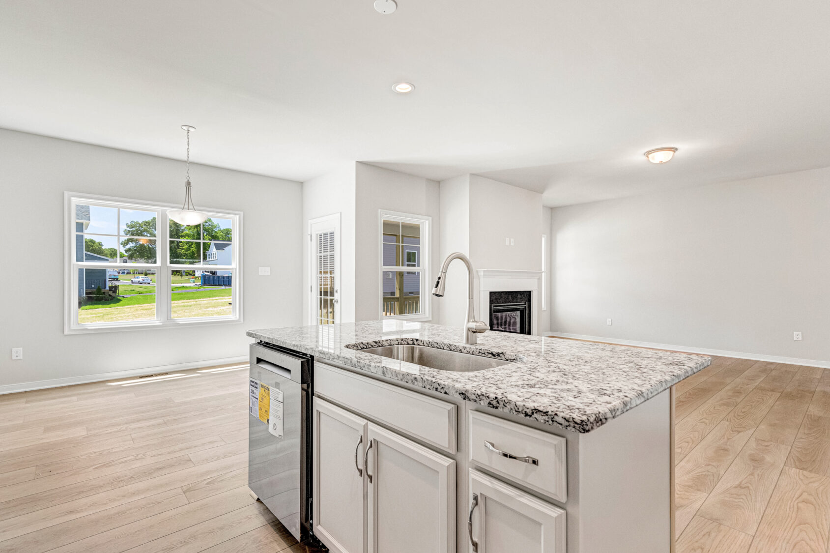 Bright, modern kitchen in Poplar Village Lot 26 with marble island, stainless steel appliances, and wood floors.