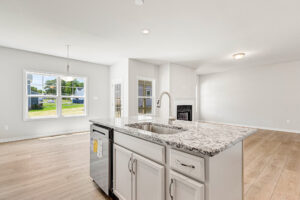 Bright, modern kitchen in Poplar Village Lot 26 with marble island, stainless steel appliances, and wood floors.