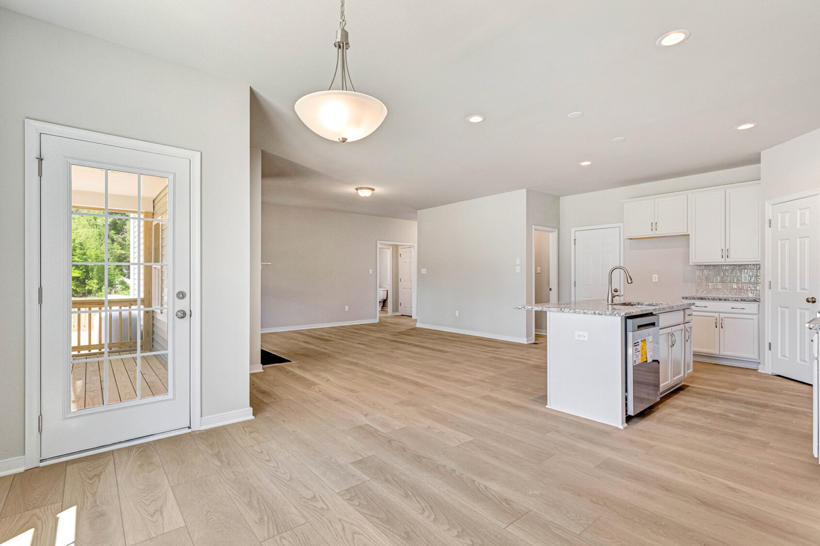 Bright, modern open-plan kitchen and living area with light wood floors and large windows in Poplar Village Lot 26.