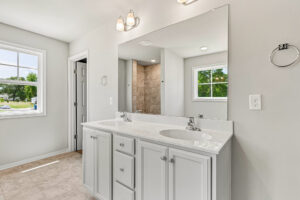 Modern bathroom in Poplar Village Lot 26 with a double sink vanity, large mirror, and bright natural light.