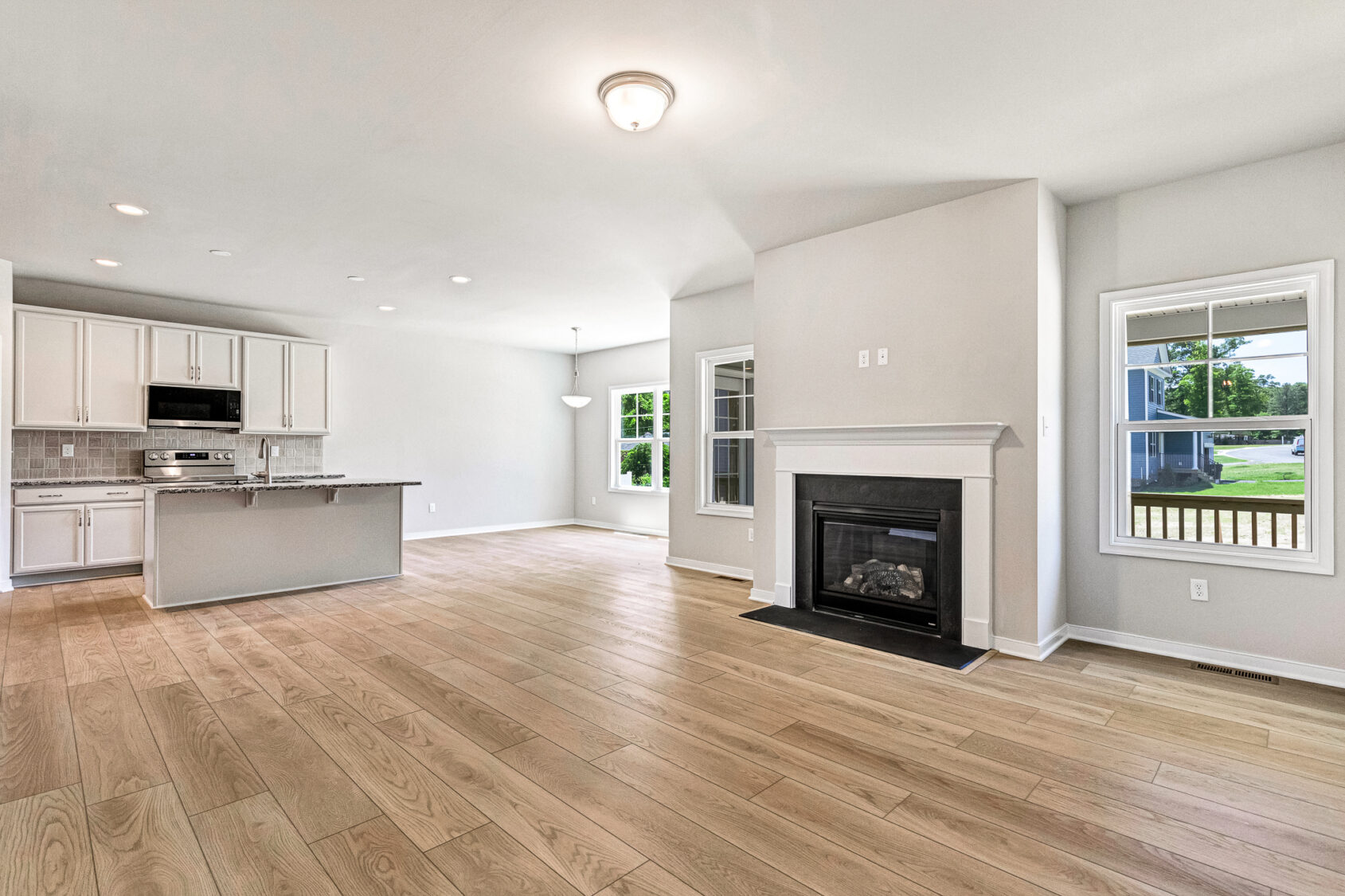 Spacious open-plan living area with wood floors, fireplace, and a modern kitchen in Poplar Village's Lot 26.