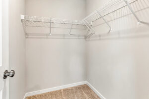 Empty walk-in closet with beige carpet, white walls, and white wire shelving in Poplar Village Lot 26.