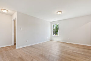Bright, empty room in Poplar Village with light wood floors, white walls, and a window letting in natural light.