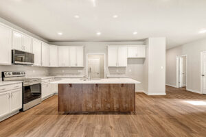 Modern kitchen at Somerset Hill Lot 8 with white cabinets, marble island, and stainless steel appliances—spacious and bright.