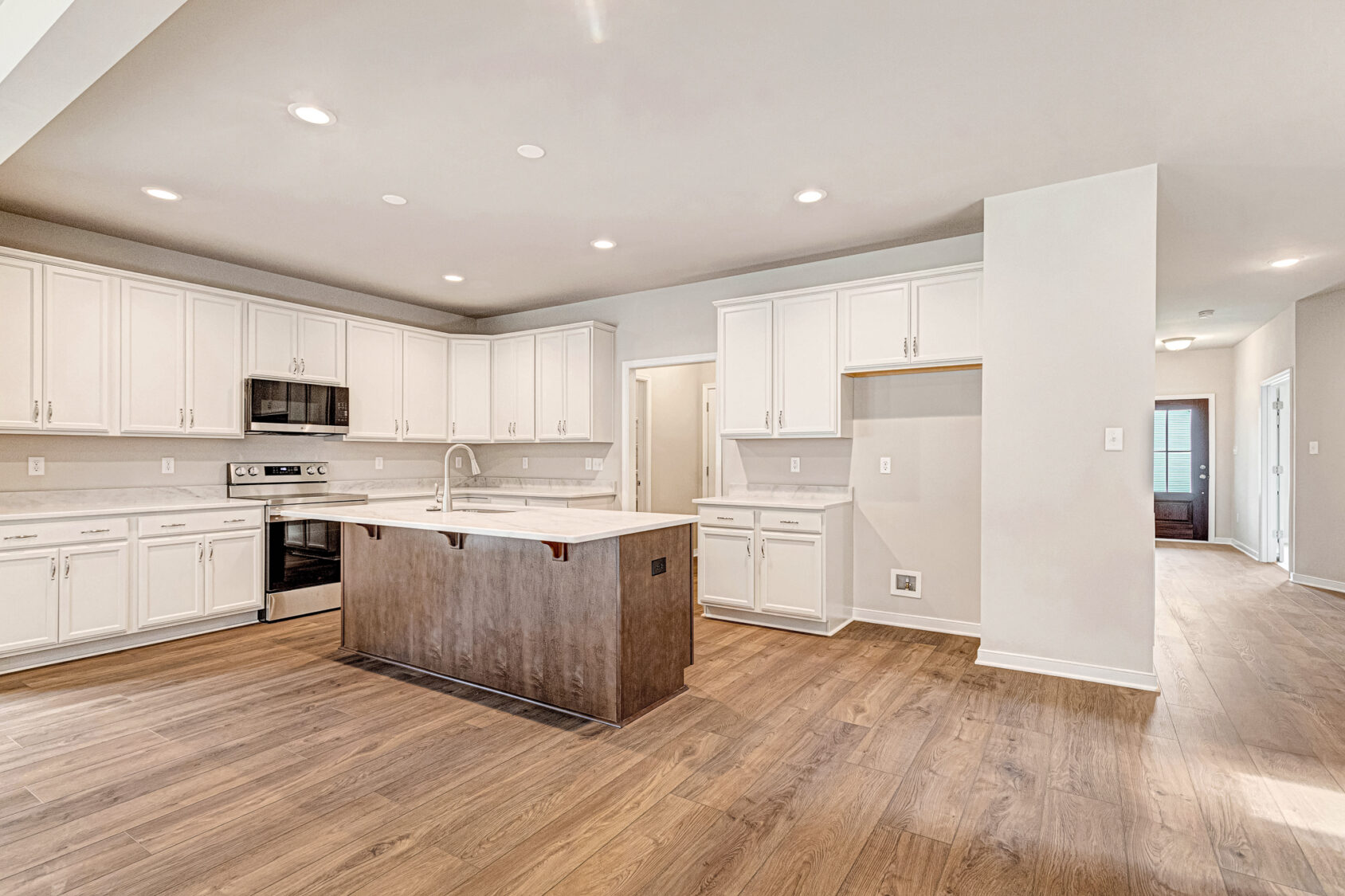 Modern Somerset Hill kitchen with white cabinets, wood floors, an island sink, and stainless steel appliances.