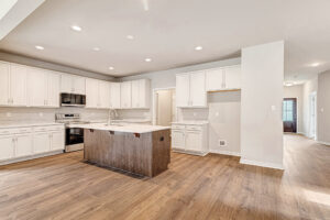 Modern Somerset Hill kitchen with white cabinets, wood floors, an island sink, and stainless steel appliances.