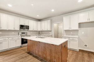 Modern kitchen at Somerset Hill Lot 8: white cabinets, wood island, marble counters, stainless appliances, wood floor.