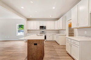 Modern kitchen in Lot 8, Somerset Hill, with white cabinets, stainless appliances, island, wood floor, and walk-in pantry.