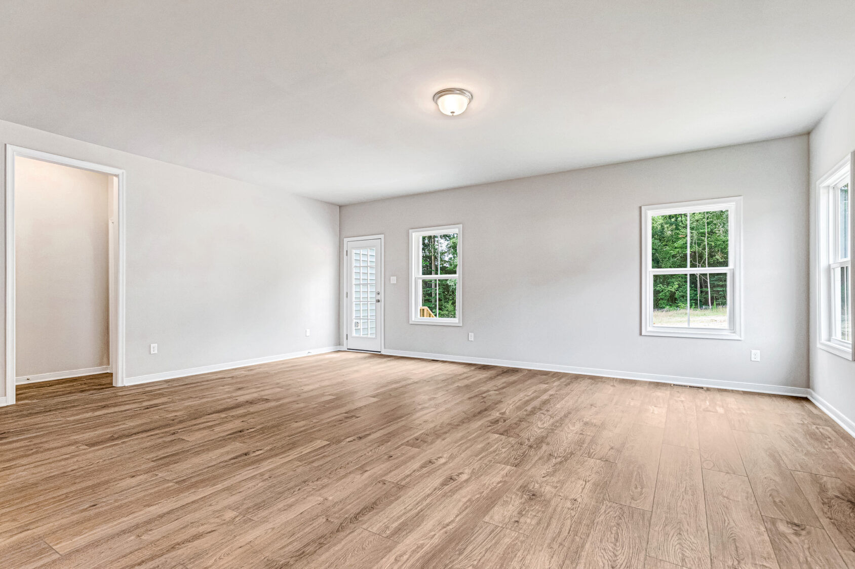 Bright, empty Somerset Hill room with light wood floors, white walls, three windows, and a ceiling light fixture.