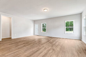 Bright, empty Somerset Hill room with light wood floors, white walls, three windows, and a ceiling light fixture.