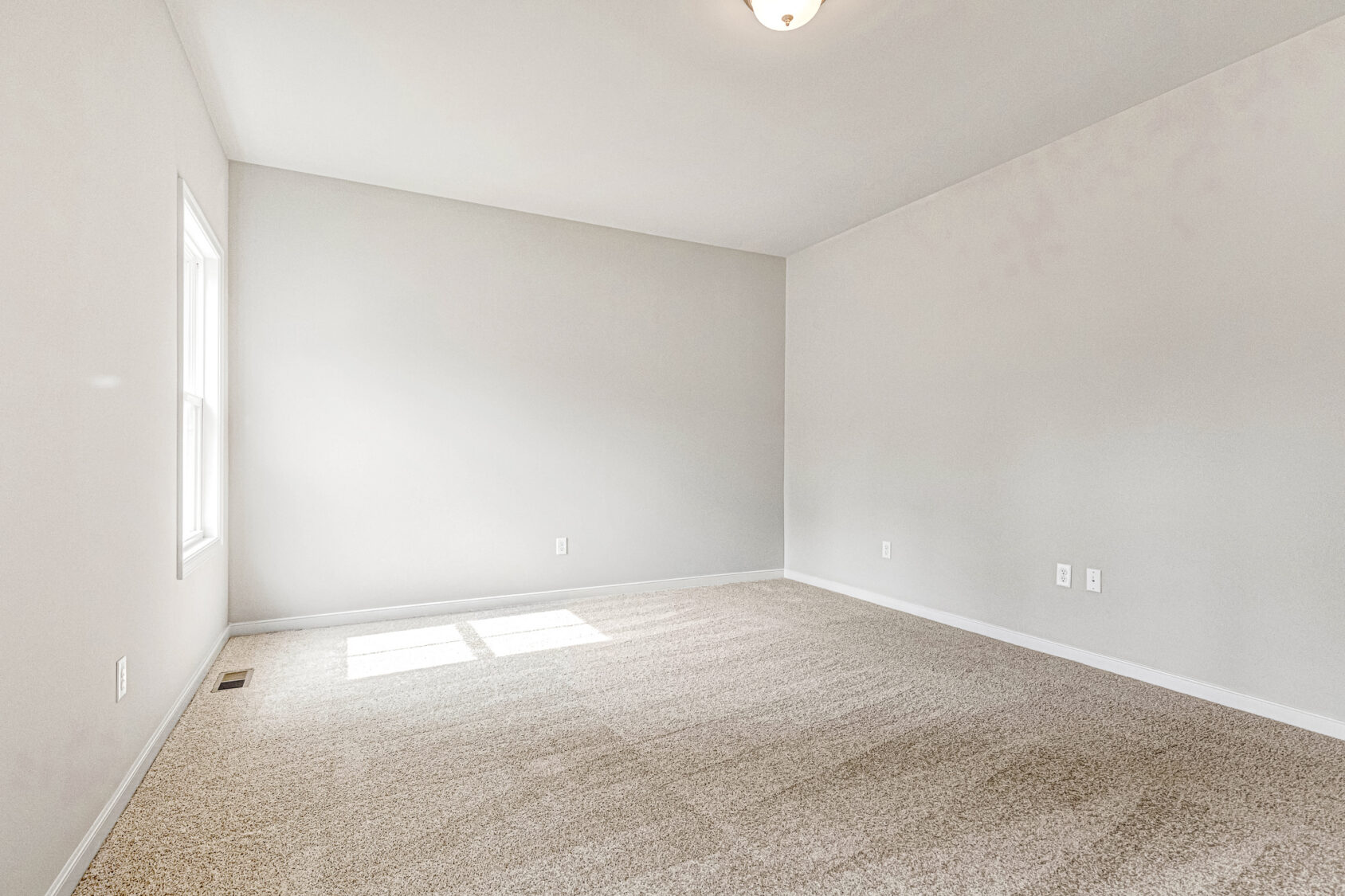 Empty room in Somerset Hill with beige carpet, light gray walls, and sunlight streaming in—welcome to Lot 8.