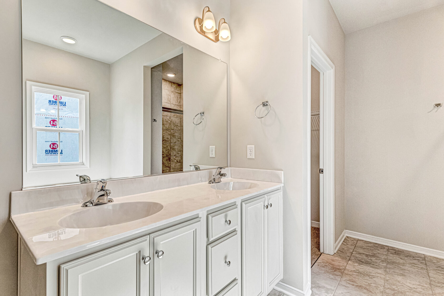 Bright Somerset Hill bathroom with double sinks, large mirror, white cabinets, light fixture, and tile floor.