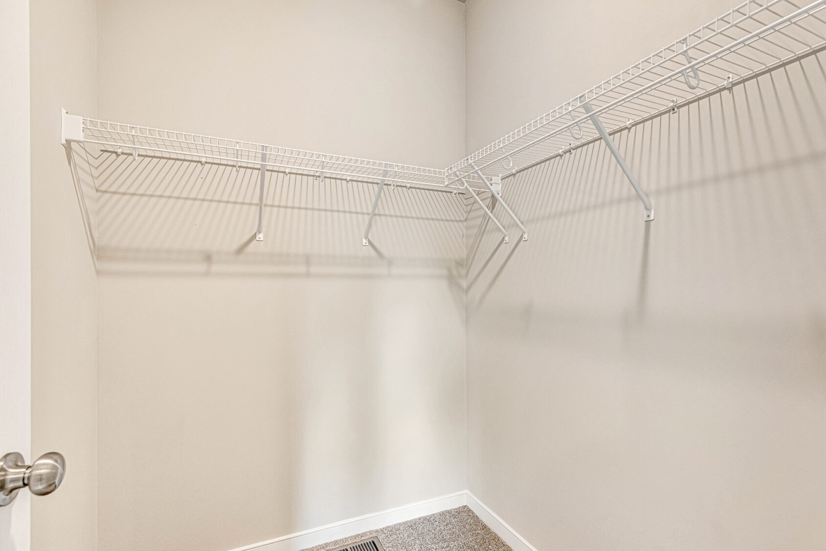 Empty walk-in closet with beige walls, white wire shelves, and silver door handle; part of Somerset Hill Lot 8.