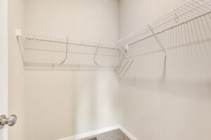Empty walk-in closet with beige walls, white wire shelves, and silver door handle; part of Somerset Hill Lot 8.