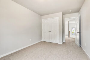 Bright, empty room in Somerset Hill with beige carpet, white walls, double closet doors, and an open hallway door.