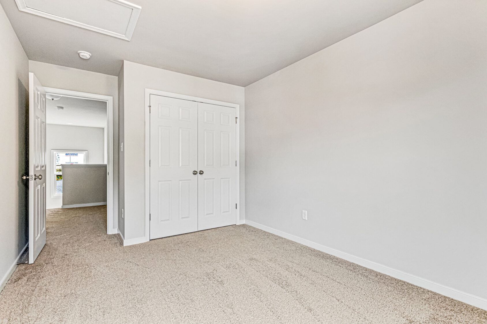 Empty beige-carpeted room in Somerset Hill with white walls, double closet doors, and open door to hallway; Lot 8.