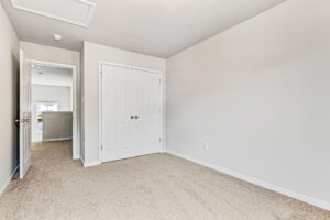 Empty beige-carpeted room in Somerset Hill with white walls, double closet doors, and open door to hallway; Lot 8.