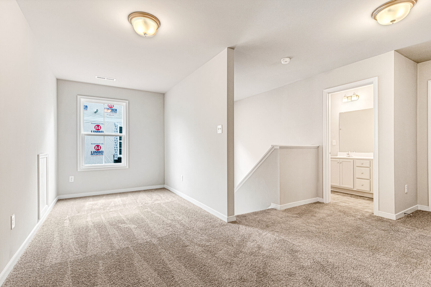 Carpeted Somerset Hill room with window, ceiling lights, and open doorway to bathroom with sink and mirror. Lot 8.
