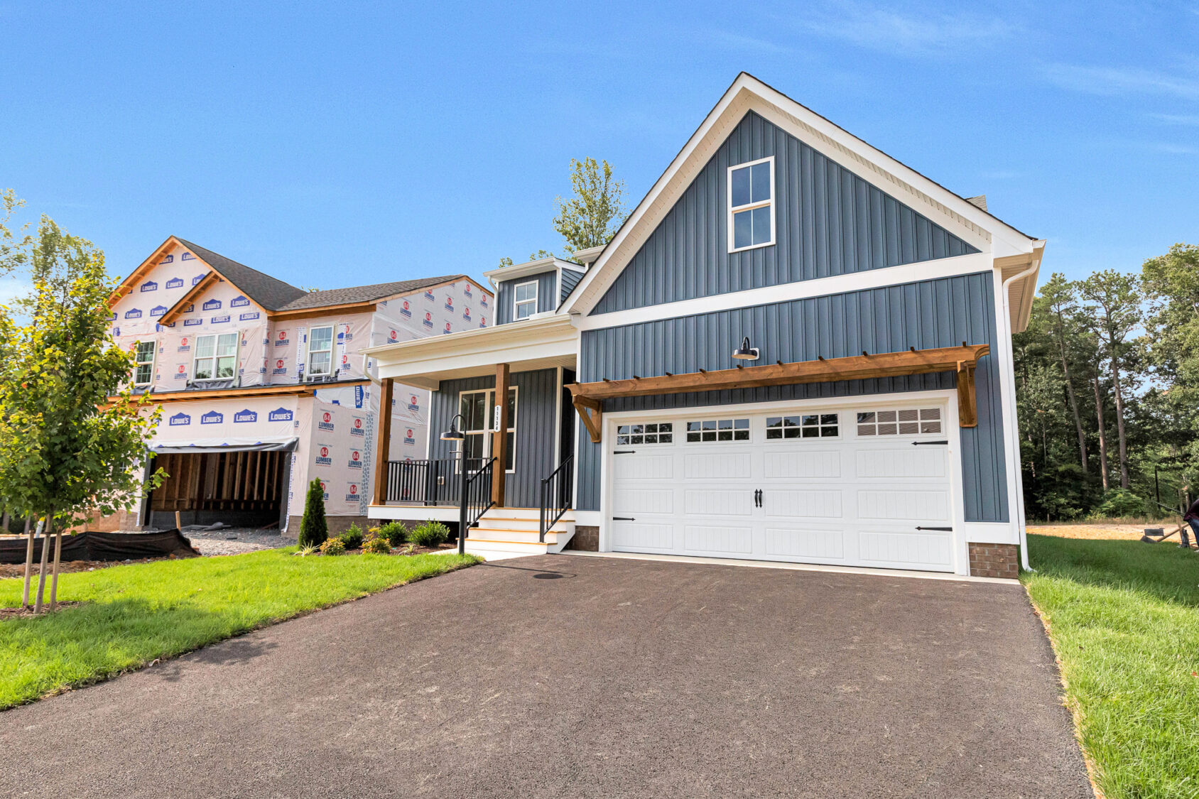 New blue house with white trim on Somerset Hill, Lot 8, features a double garage near a home under construction.