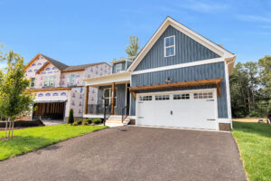 New blue house with white trim on Somerset Hill, Lot 8, features a double garage near a home under construction.