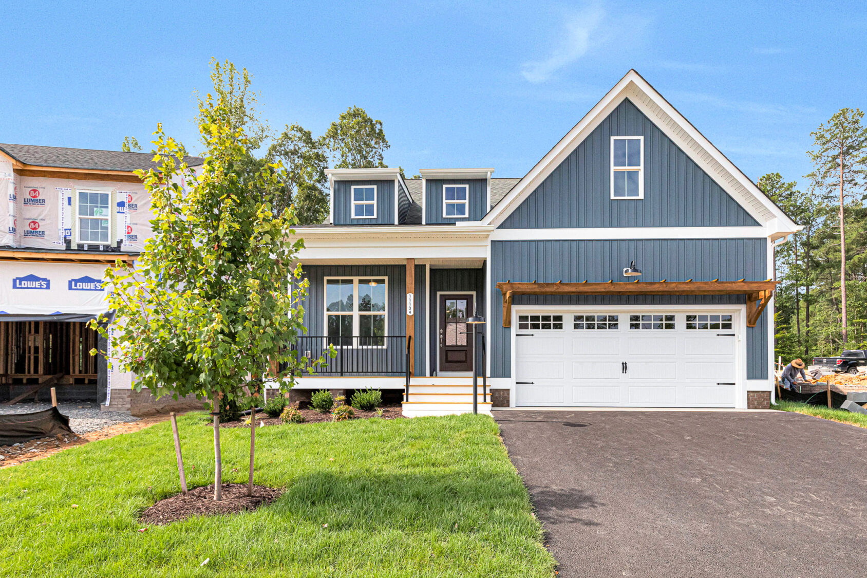 Blue two-story house with white trim on Lot 8, Somerset Hill; new landscaping, front porch, garage, clear blue sky.