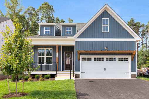 Blue house with white trim on Lot 8, Somerset Hill, features a porch, double garage, lawn, and small front tree.