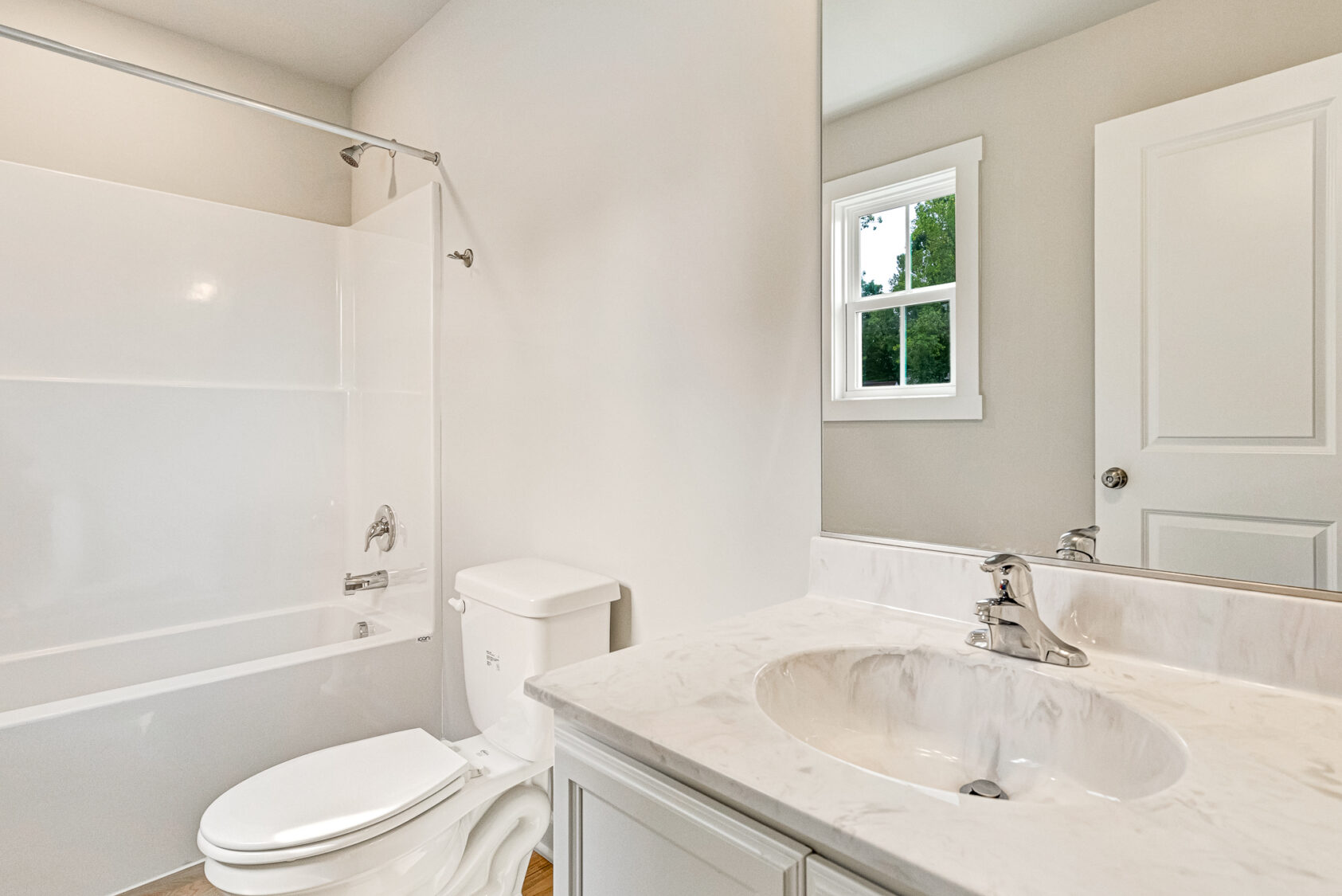 White bathroom in Poplar Village with bathtub, marble sink, and window. Experience Lot 7’s natural light charm.