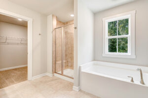Bathroom in Lot 7, Poplar Village, features a white tub, glass shower, window, and carpeted open closet with wire shelves.